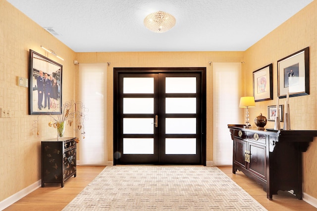 entrance foyer with a textured ceiling, light hardwood / wood-style flooring, and a healthy amount of sunlight