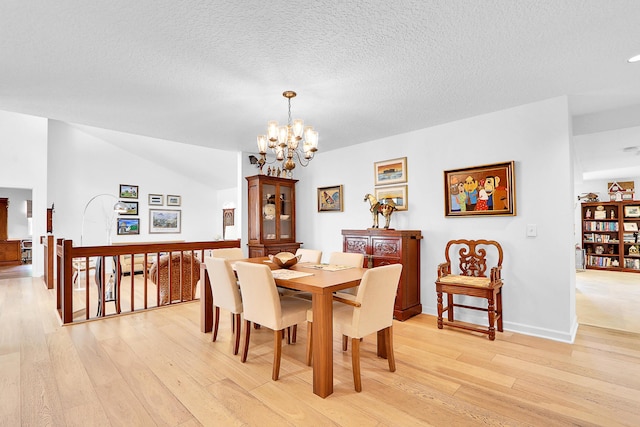 dining room with a textured ceiling, light hardwood / wood-style flooring, and a notable chandelier