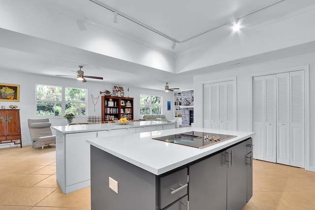 kitchen featuring plenty of natural light, light tile patterned floors, track lighting, black electric cooktop, and a kitchen island