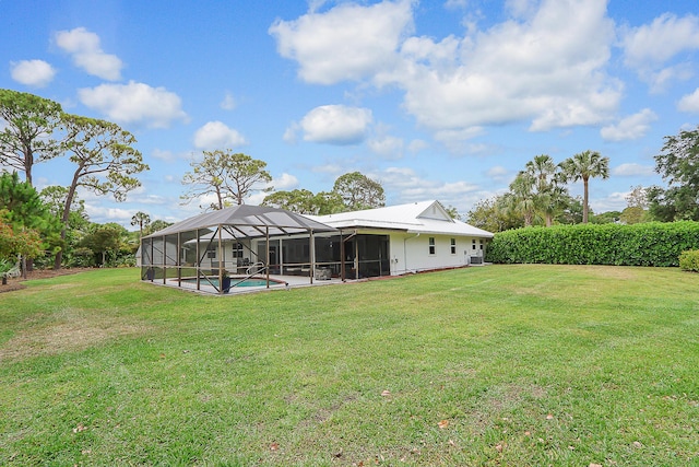 rear view of house with glass enclosure and a lawn