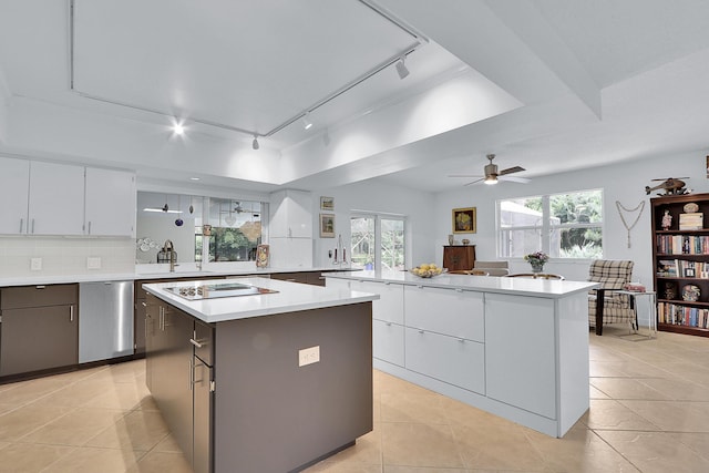 kitchen featuring a kitchen island, black electric cooktop, stainless steel dishwasher, and tasteful backsplash