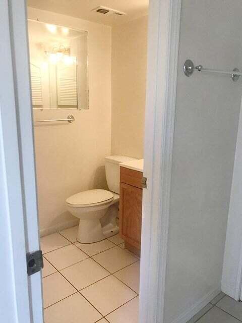 bathroom featuring toilet, tile flooring, and vanity