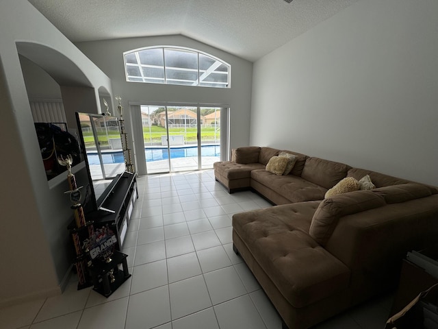 tiled living room featuring a textured ceiling and high vaulted ceiling