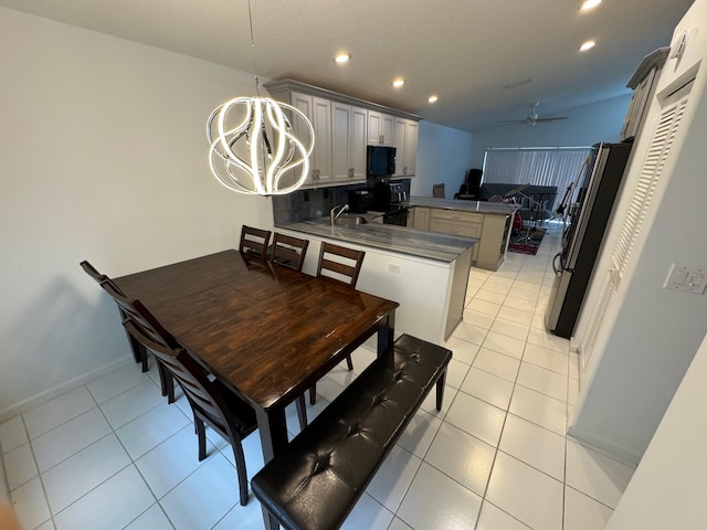 tiled dining room featuring sink and ceiling fan with notable chandelier