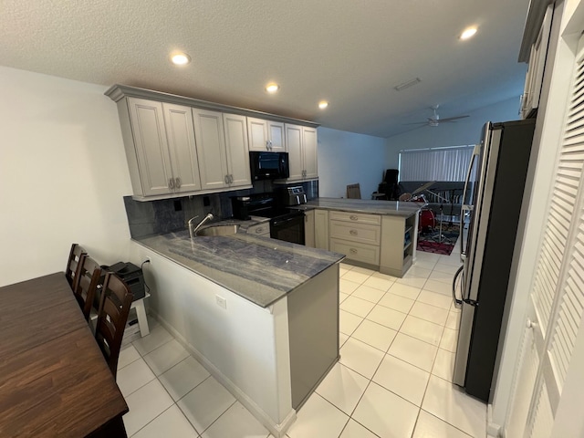 kitchen with black appliances, light tile patterned flooring, backsplash, ceiling fan, and kitchen peninsula