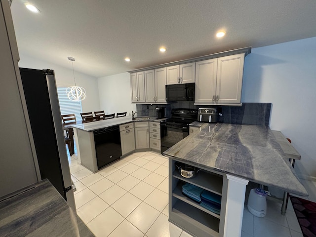 kitchen featuring light tile patterned floors, backsplash, kitchen peninsula, black appliances, and decorative light fixtures