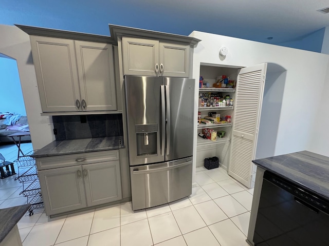 kitchen with tasteful backsplash, light tile patterned floors, stainless steel refrigerator with ice dispenser, and gray cabinets