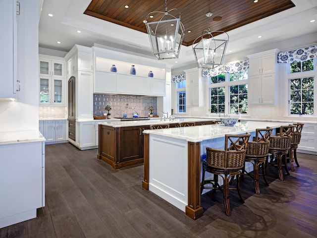 kitchen featuring a center island, dark wood-type flooring, wooden ceiling, and a tray ceiling