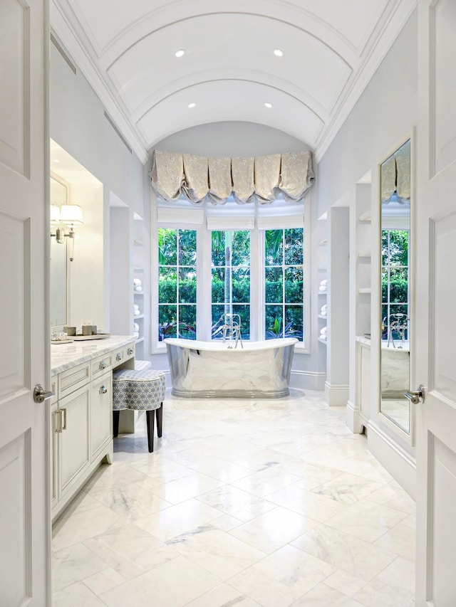 bathroom with tile floors, a bathing tub, vanity, and lofted ceiling