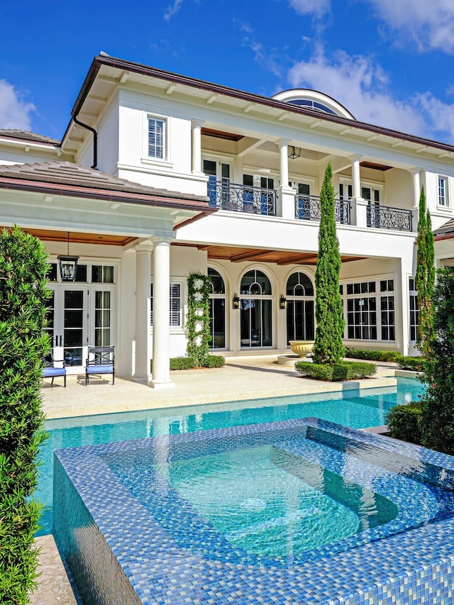 rear view of house with a patio area, french doors, and a balcony