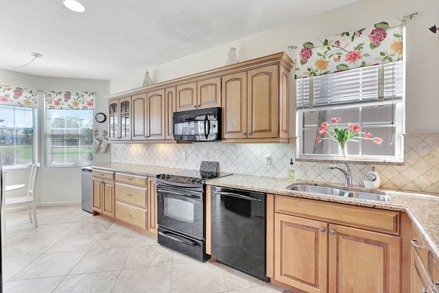 kitchen with light stone counters, tasteful backsplash, light tile floors, and black appliances