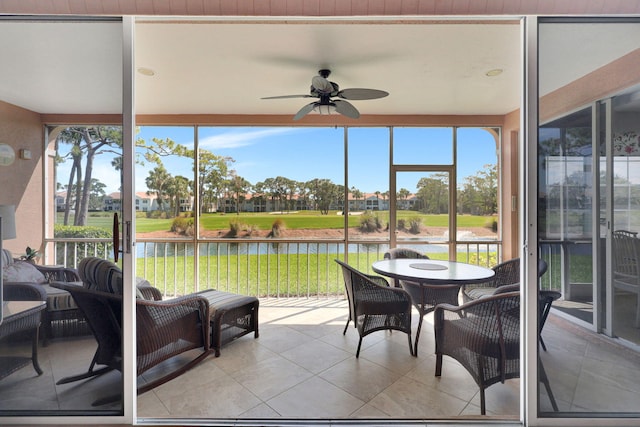 sunroom / solarium with plenty of natural light, ceiling fan, and a water view