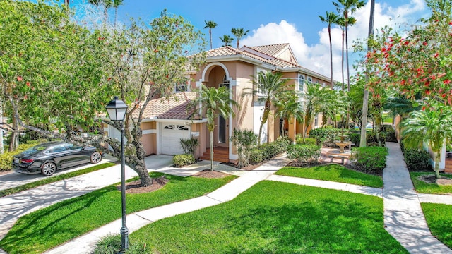 mediterranean / spanish house with concrete driveway, a front lawn, a tile roof, and stucco siding