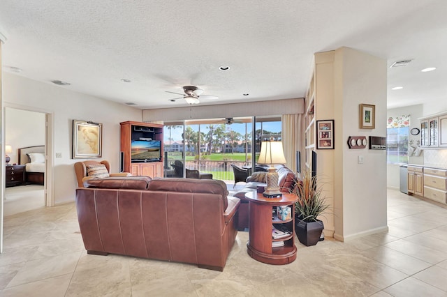 tiled living room with built in shelves, ceiling fan, and a textured ceiling