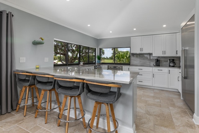 kitchen featuring backsplash, light stone countertops, white cabinets, and light tile flooring