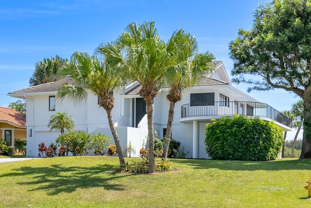 view of front of house featuring a garage, a balcony, and a front lawn