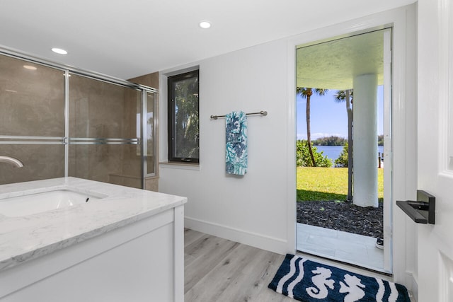 bathroom featuring walk in shower, wood-type flooring, vanity, and a water view