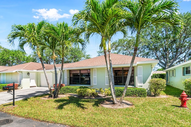 view of front of property featuring a garage, driveway, a front yard, and stucco siding