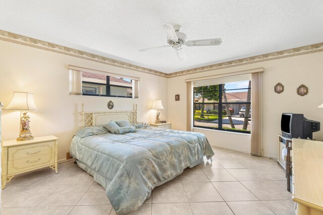 bedroom featuring light tile patterned floors, a ceiling fan, baseboards, and a textured ceiling