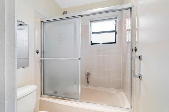 bathroom with toilet and shower / bath combination with glass door