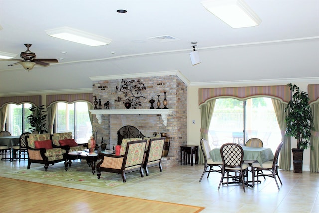 living area featuring ornamental molding, a brick fireplace, visible vents, and a healthy amount of sunlight