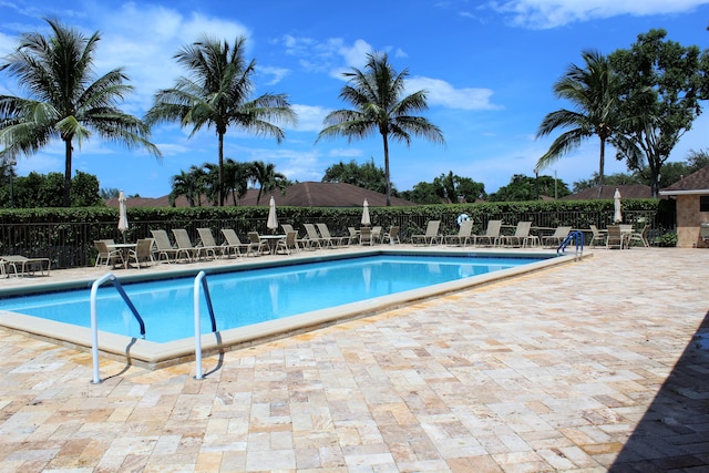 pool with a patio area and fence