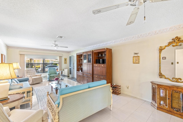 living area featuring a textured ceiling, light tile patterned flooring, visible vents, baseboards, and a ceiling fan