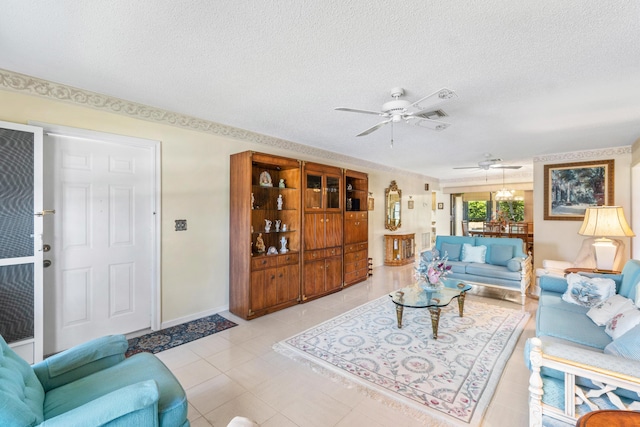 living room with a textured ceiling, ceiling fan, light tile patterned floors, and baseboards