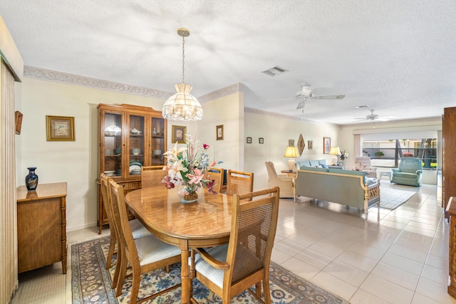 dining space with a textured ceiling, light tile patterned floors, a ceiling fan, visible vents, and baseboards