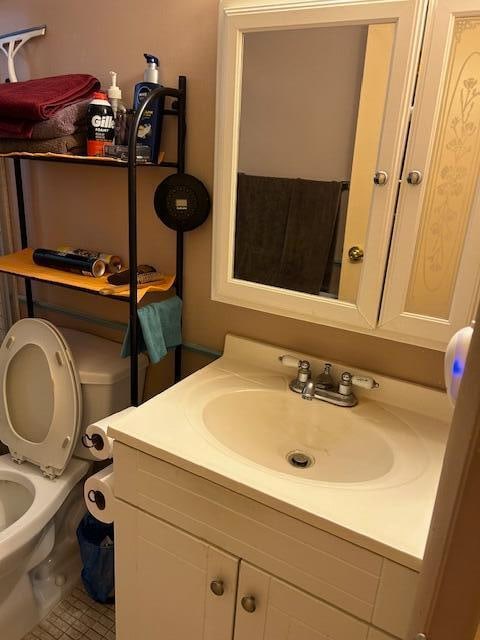 bathroom with tile flooring, vanity, and toilet