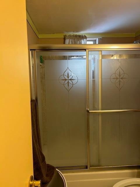 bathroom featuring shower / bath combination with glass door, toilet, and ornamental molding