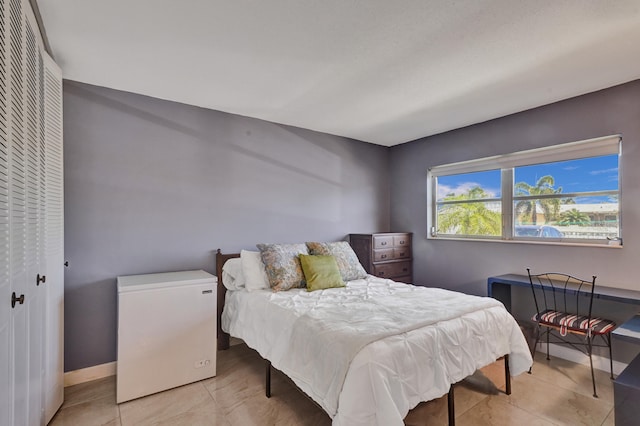 bedroom featuring a closet, light tile flooring, and fridge