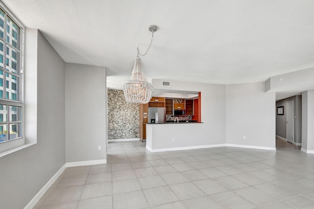 unfurnished living room with light tile patterned flooring and an inviting chandelier