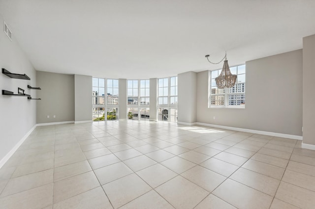 empty room featuring a chandelier and light tile patterned floors