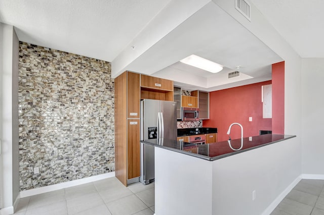 kitchen with sink, light tile patterned floors, appliances with stainless steel finishes, tasteful backsplash, and kitchen peninsula