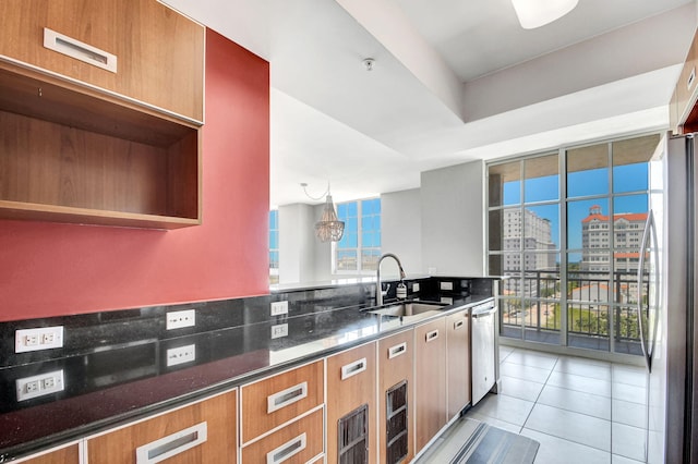 kitchen with dark stone counters, sink, light tile patterned floors, decorative light fixtures, and stainless steel appliances