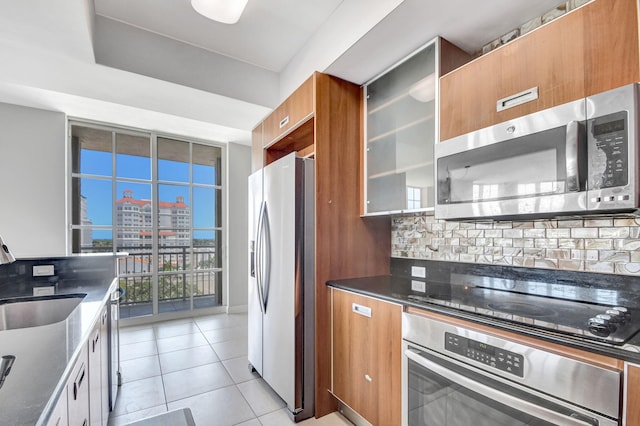 kitchen featuring decorative backsplash, light tile patterned floors, stainless steel appliances, and sink