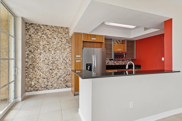 kitchen with sink, kitchen peninsula, decorative backsplash, light tile patterned floors, and appliances with stainless steel finishes