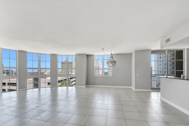 unfurnished room with light tile patterned floors, floor to ceiling windows, and a notable chandelier