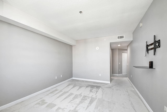 carpeted empty room with a textured ceiling