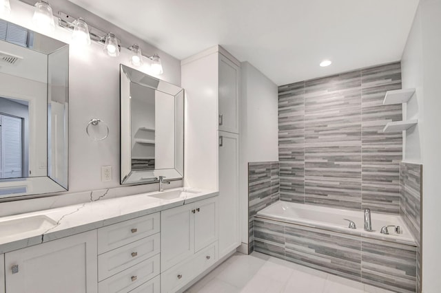 bathroom featuring tile patterned flooring, vanity, and tiled bath