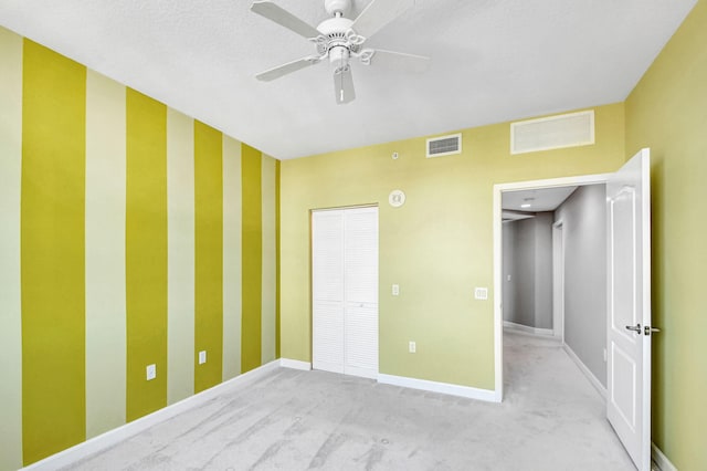 unfurnished bedroom featuring a textured ceiling, ceiling fan, and light carpet