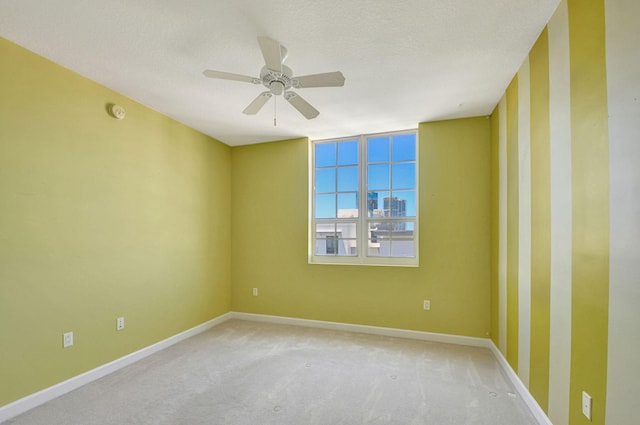 spare room with a textured ceiling, carpet floors, and ceiling fan