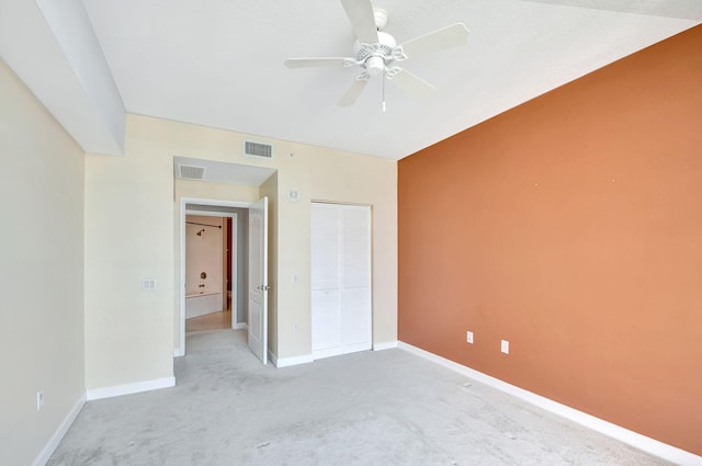 unfurnished bedroom featuring ceiling fan, light colored carpet, and a closet