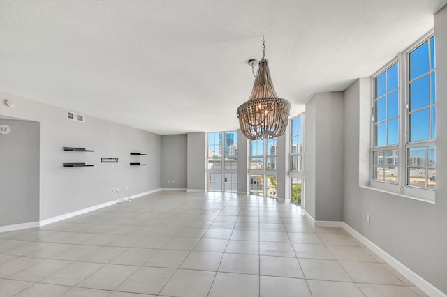 unfurnished room with a notable chandelier, plenty of natural light, light tile patterned flooring, and a textured ceiling