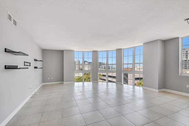 spare room with light tile patterned floors, a textured ceiling, and expansive windows