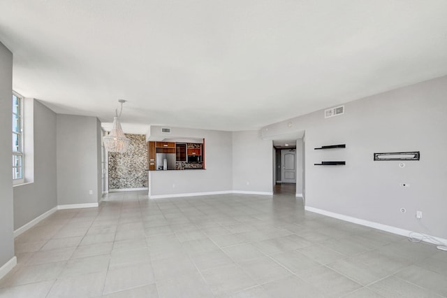 unfurnished living room featuring light tile patterned floors and an inviting chandelier