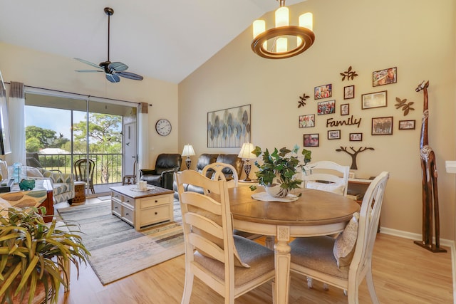 dining area featuring ceiling fan with notable chandelier, high vaulted ceiling, and light hardwood / wood-style floors