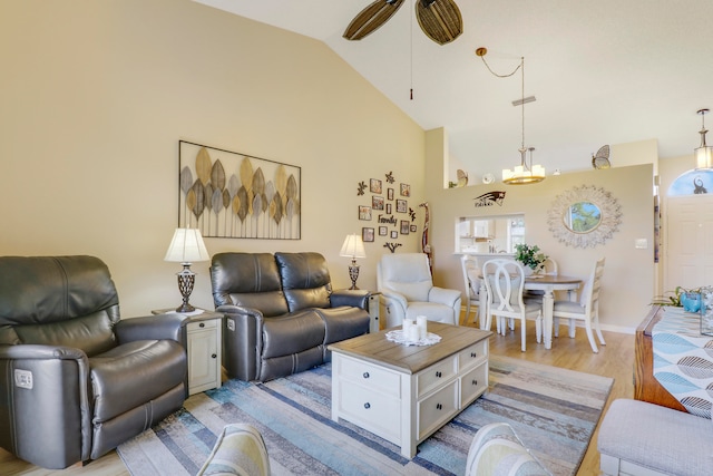 living room with ceiling fan with notable chandelier, light hardwood / wood-style floors, and vaulted ceiling