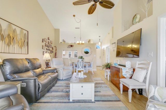 living room with high vaulted ceiling, ceiling fan, and light wood-type flooring